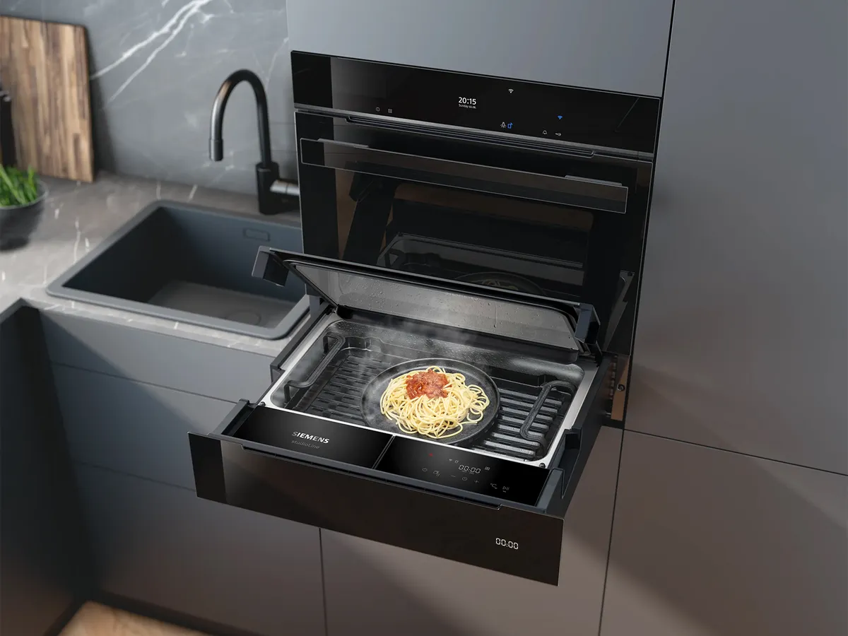 Moderne Küche mit einem in die Schränke integrierten Siemens Dampfschublade, der Pasta aufgewärmt wird.