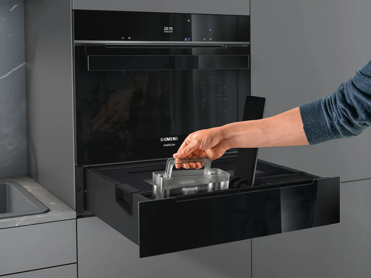 Eine Person entnimmt den Wassertank aus der Siemens Dampfschublade