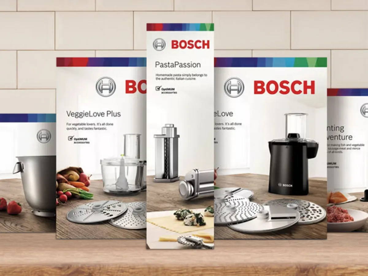 Кухненски уреди Bosch, включително блендер, кухненски робот и кафемашина, изложени на дървена повърхност.
