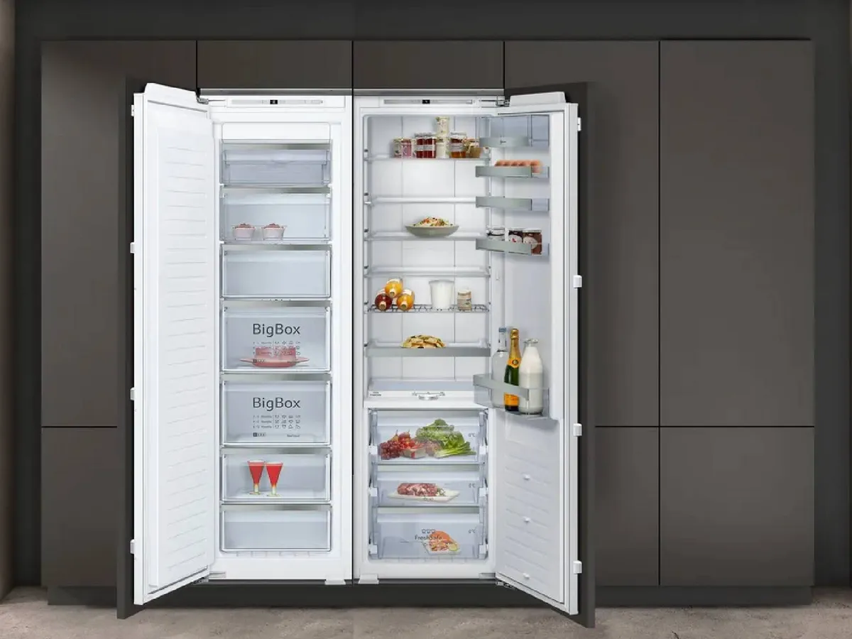 To åpne, integrerte, kjøleskap side-by-side med matvarer pent organisert på hyller og i kjøkkenskapsdøren.