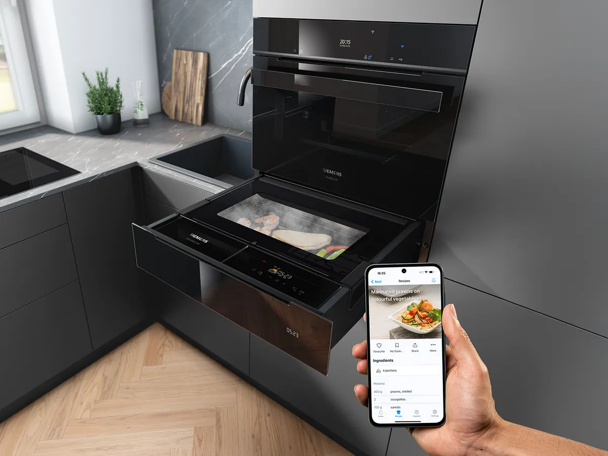 Ein Siemens Dampfofen in einer modernen Küche mit einer Hand, die ein Smartphone mit einer Rezept-App hält.
