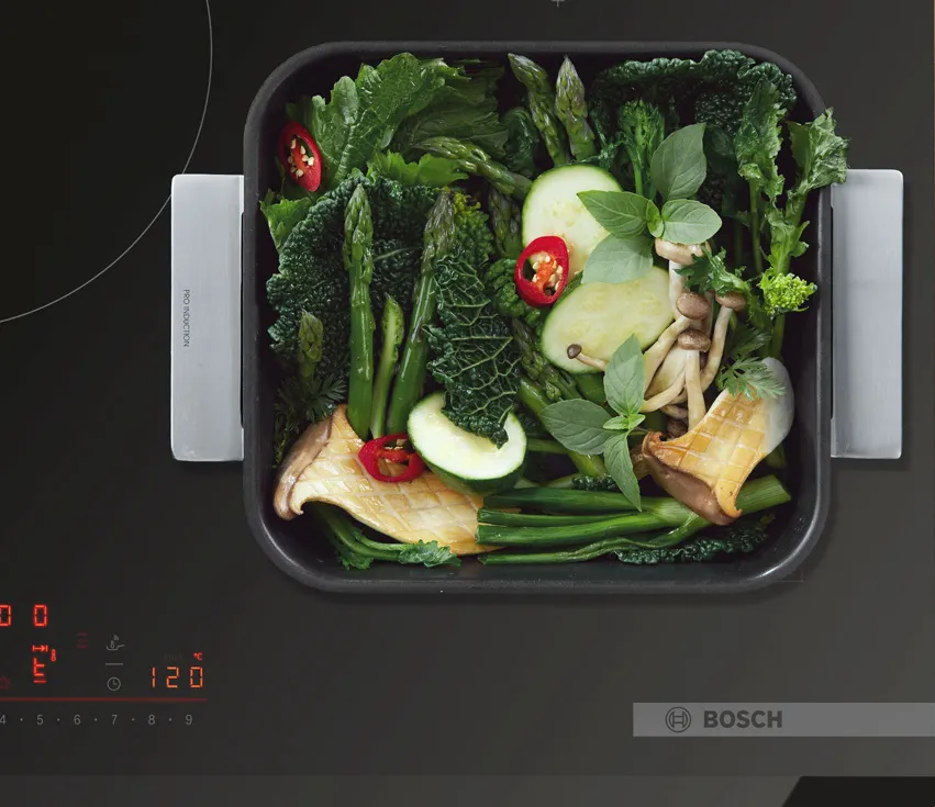 Stainless steel roasting pan with handles, with green veg inside.