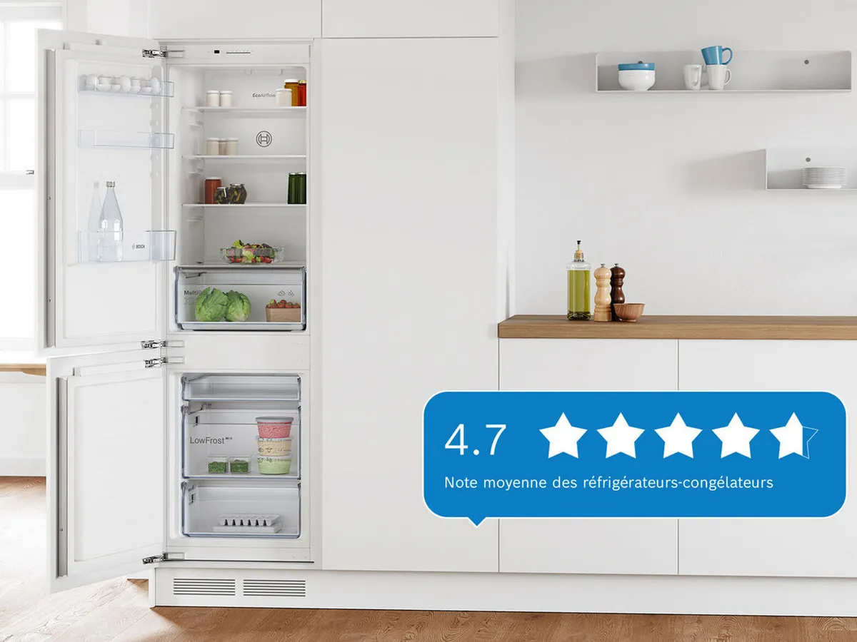 Une cuisine avec un réfrigérateur Bosch blanc, partiellement ouvert, affichant une note de 4,7 étoiles sur le côté.