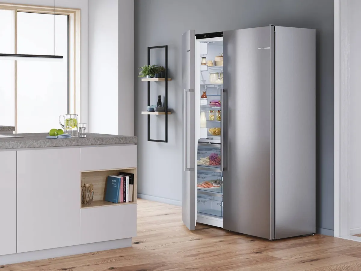 Cuisine moderne avec Frigos américain Bosch inox, porte ouverte sur les aliments.