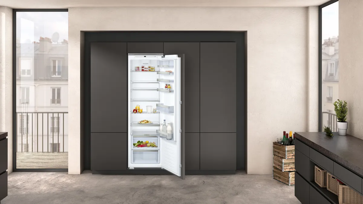 A built-in open fridge-freezer combination to the right of a large window.
