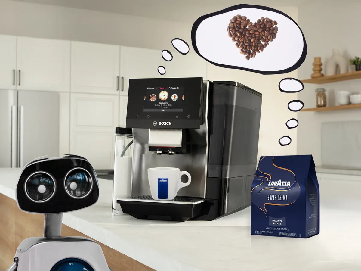 A robot with large eyes watches a Bosch coffee machine preparing a cappuccino. Above it, a thought bubble shows a heart made of coffee beans. Next to the machine is a bag of Lavazza Super Crema whole bean coffee. The background features a modern, minimalist kitchen.