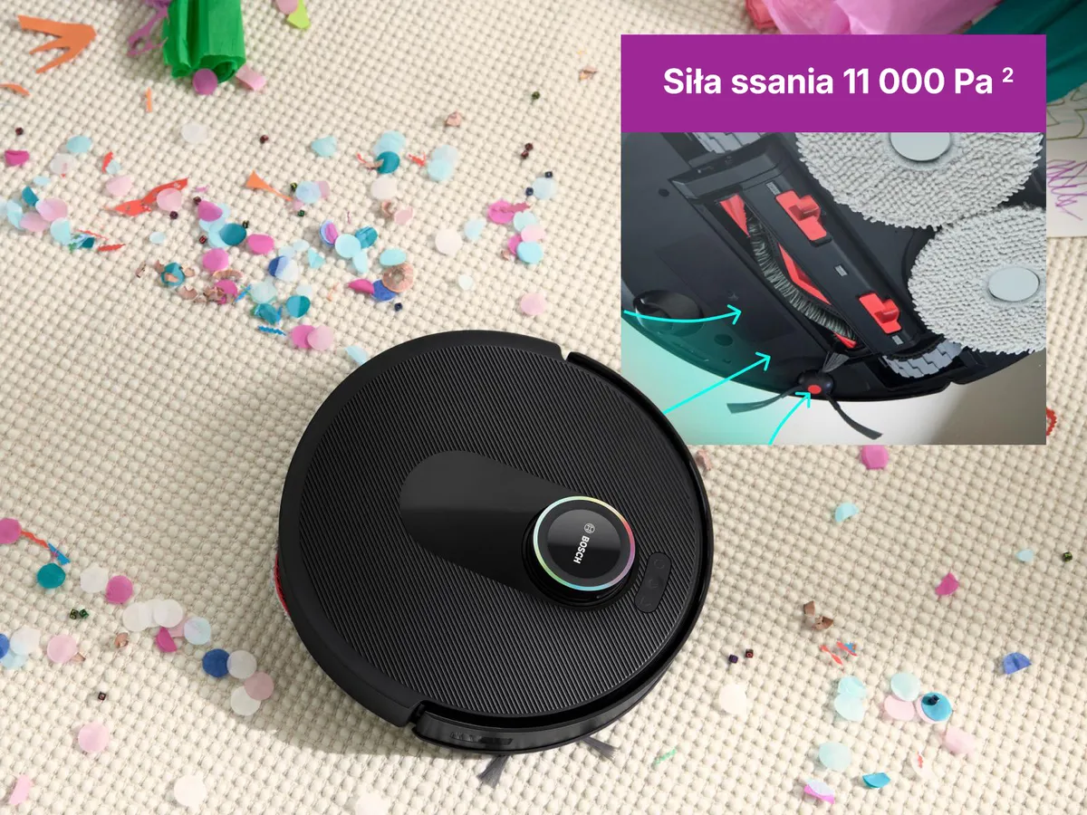 Robot Spotless na białym dywanie, torujący sobie drogę przez confetti, pokazując swoją moc ssania.
