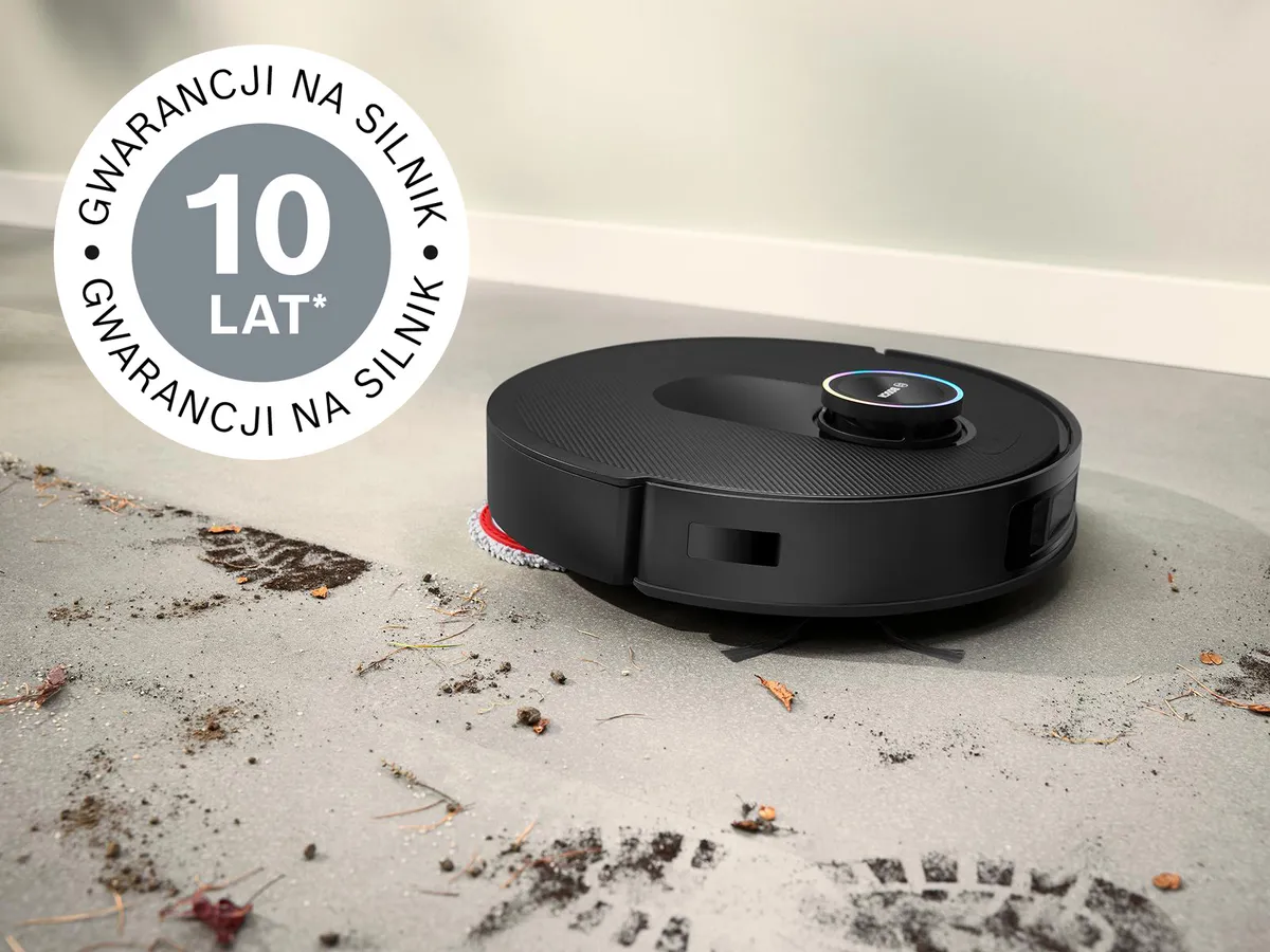 Robot Spotless usuwa błoto z białych płytek, w jego lewym górnym rogu znajduje się odznaka 10-letniej gwarancji na silnik.