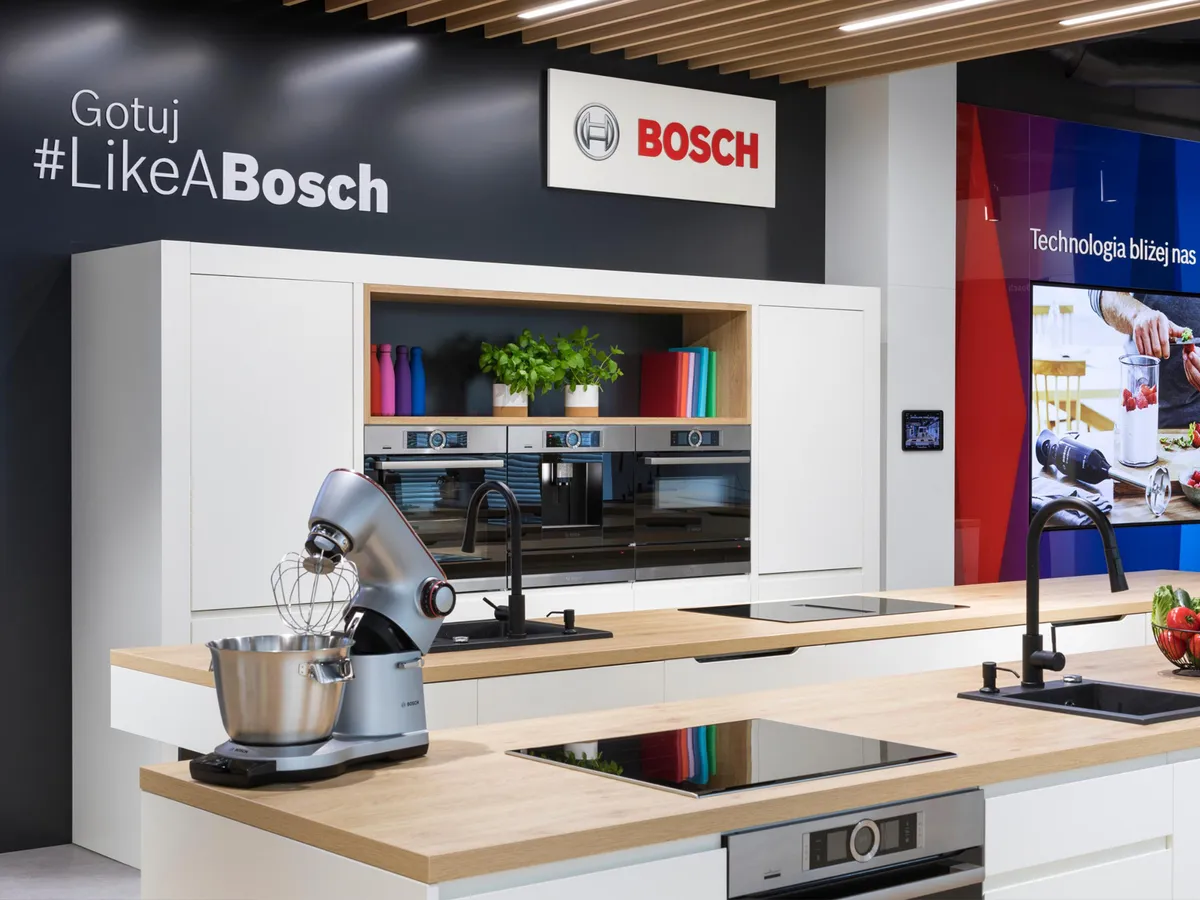 Nowoczesne studio kuchenne Boscha z białymi szafkami, piekarnikami do zabudowy, sprzętem AGD…