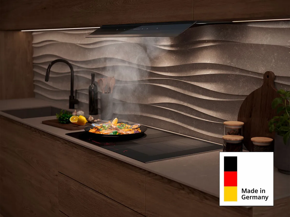 Moderne Küche mit einem Herd, auf dem Essen zubereitet wird, wellenförmigem Rückwand und Unterbaubeleuchtung.