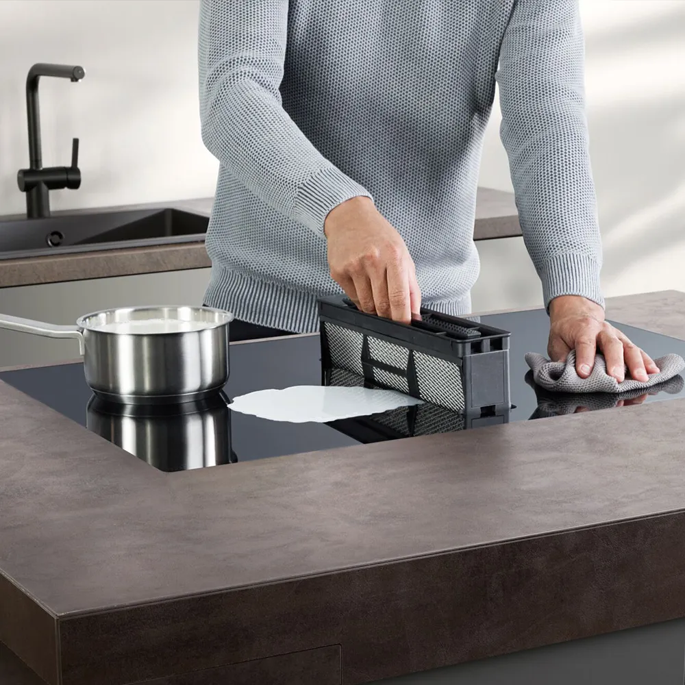 A man vacuums a countertop, effectively removing dust and debris from the surface. 