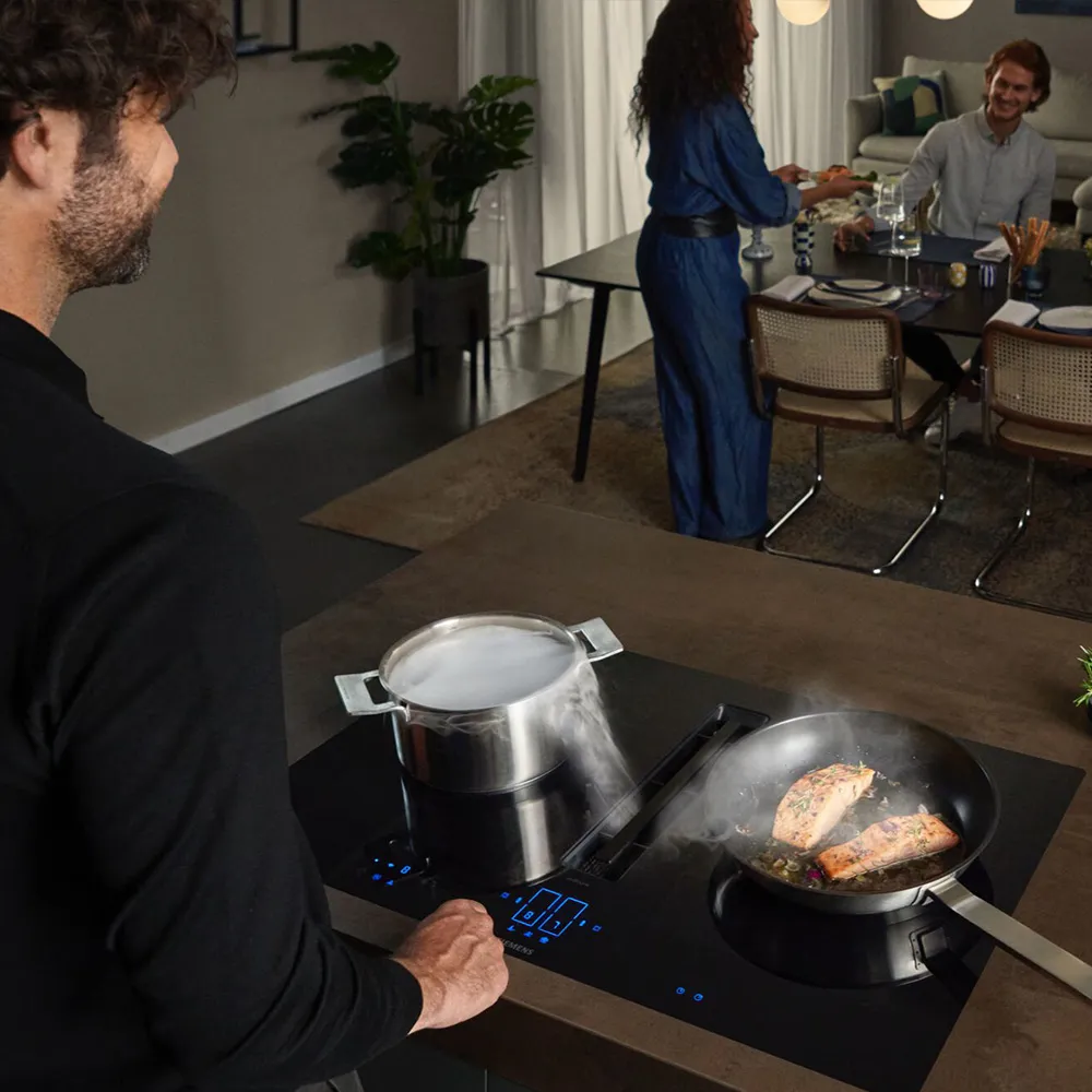 A man and woman cooking together on an induction cooktop in a modern kitchen. 
