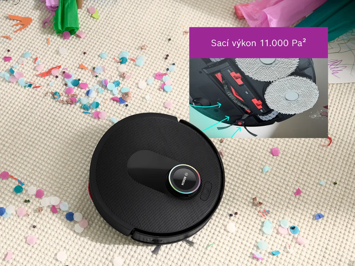 Robot Spotless na bílé koberci, který vyčistí cestu skrze konfety a předvádí svou sací sílu.