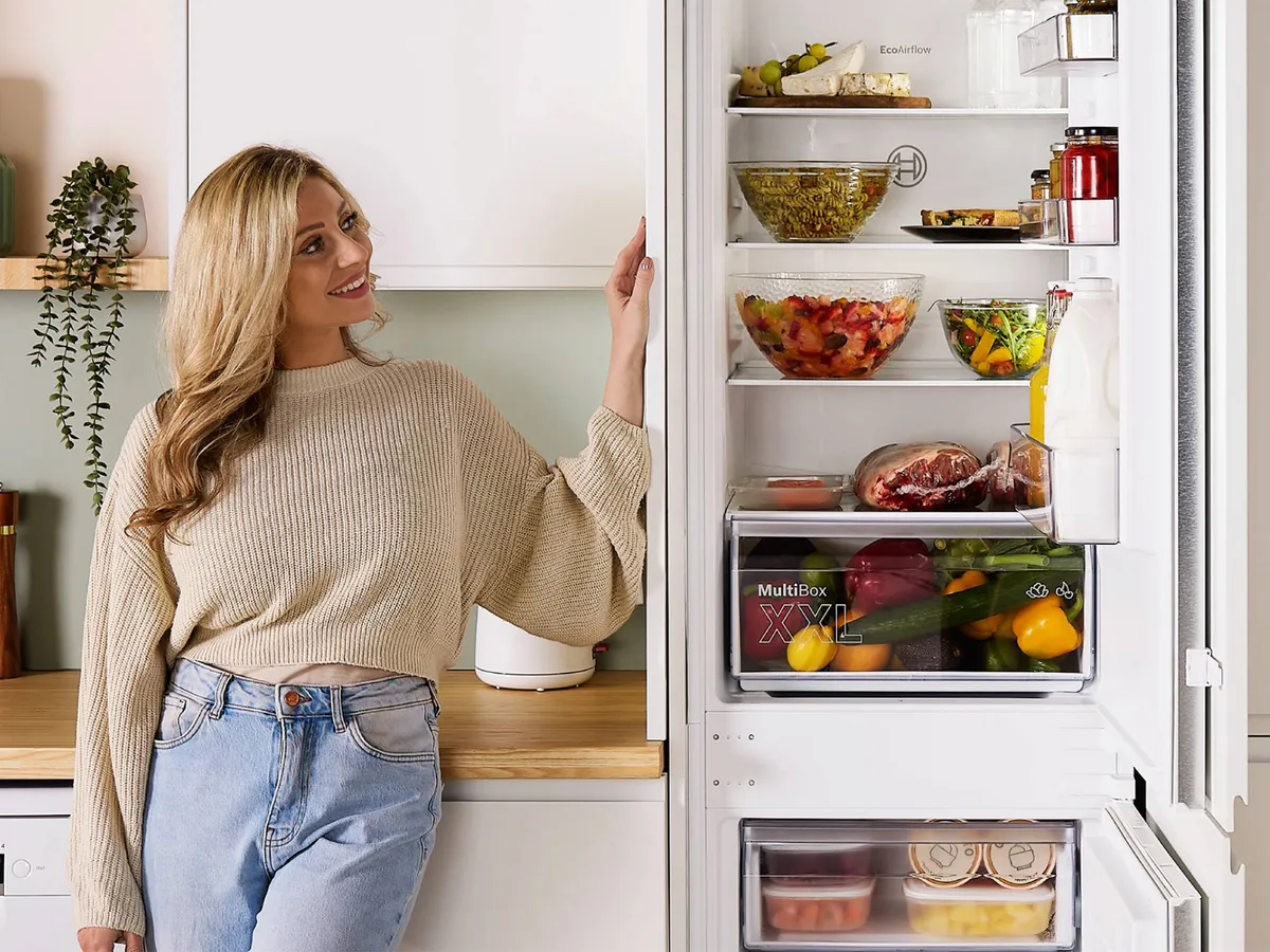 Person stood next to open fridge freezer