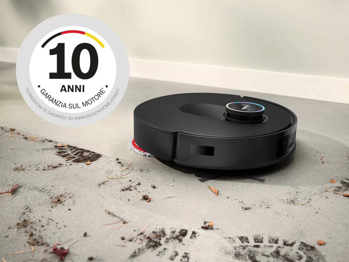 Spotless pulisce il fango dalle piastrelle bianche, con un badge di garanzia del motore di 10 anni nell'angolo in alto a sinistra.