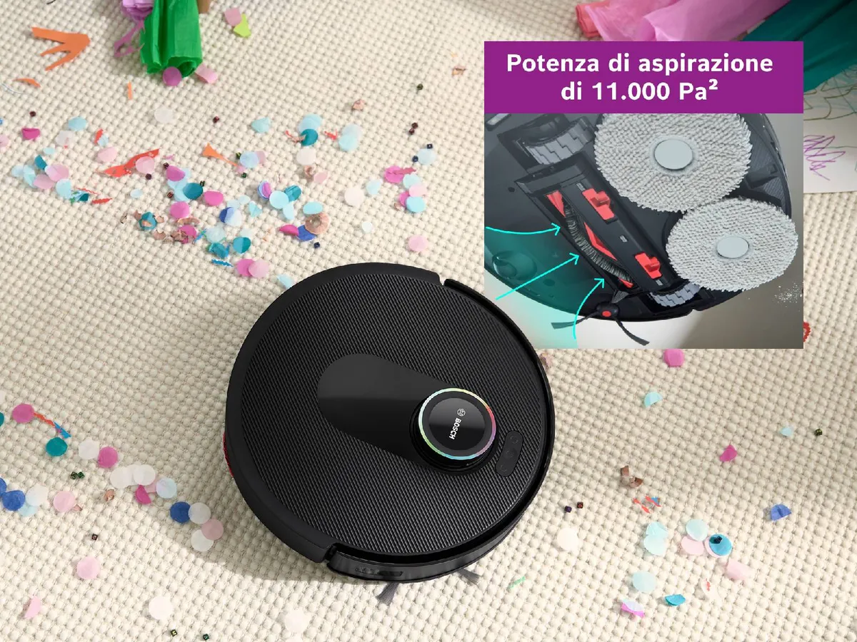 Spotless su un tappeto bianco, che pulisce un percorso tra i coriandoli, mettendo in mostra la sua potenza di aspirazione.