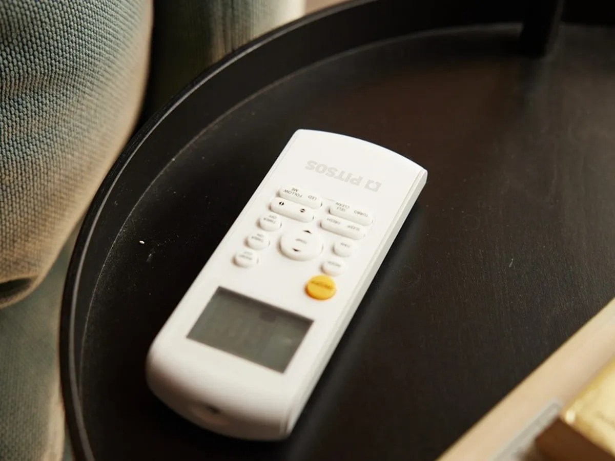 Ένα τηλεχειριστήριο air condition πάνω σε μικρό κυκλικό τραπεζάκι δίπλα από τον καναπέ.