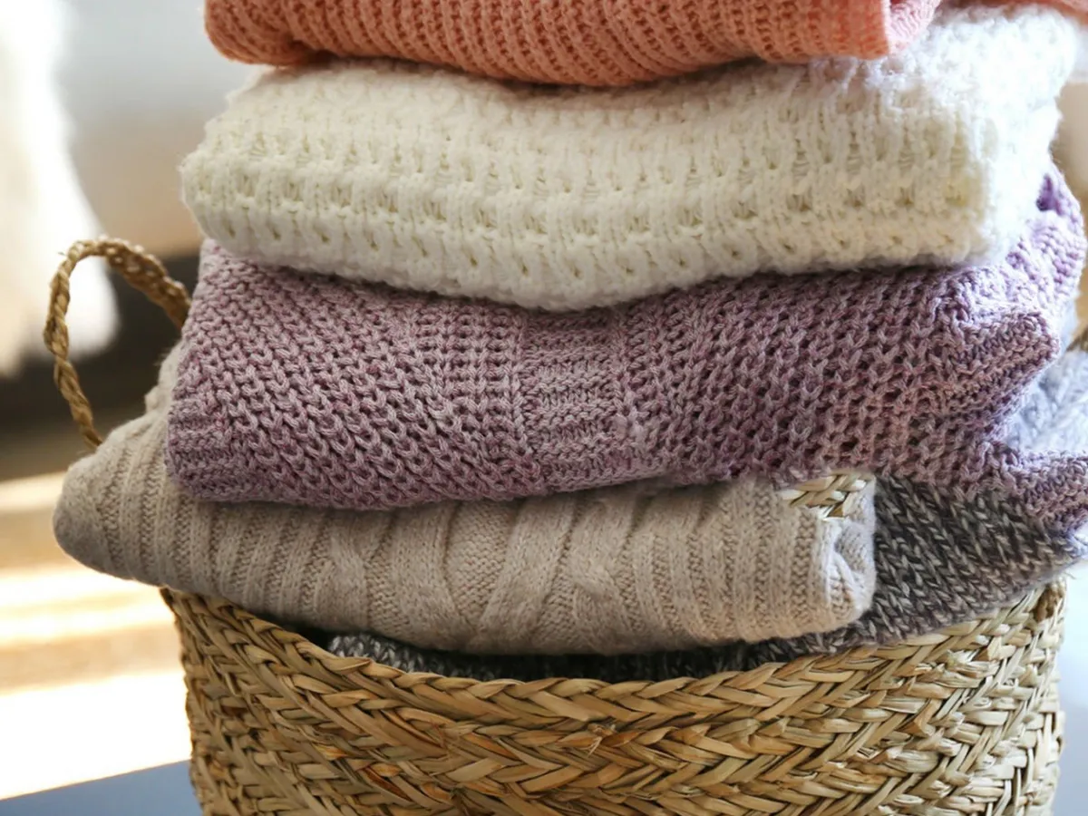 Ένα ψάθινο καλάθι με πλυμένα, διπλωμένα πουλόβερ.