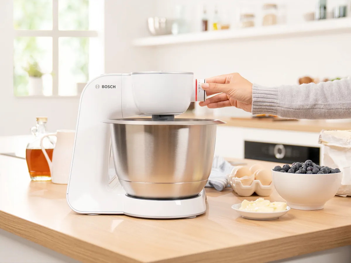 A Bosch kitchen mixer in a modern kitchen setting with ingredients like blueberries and butter nearby.