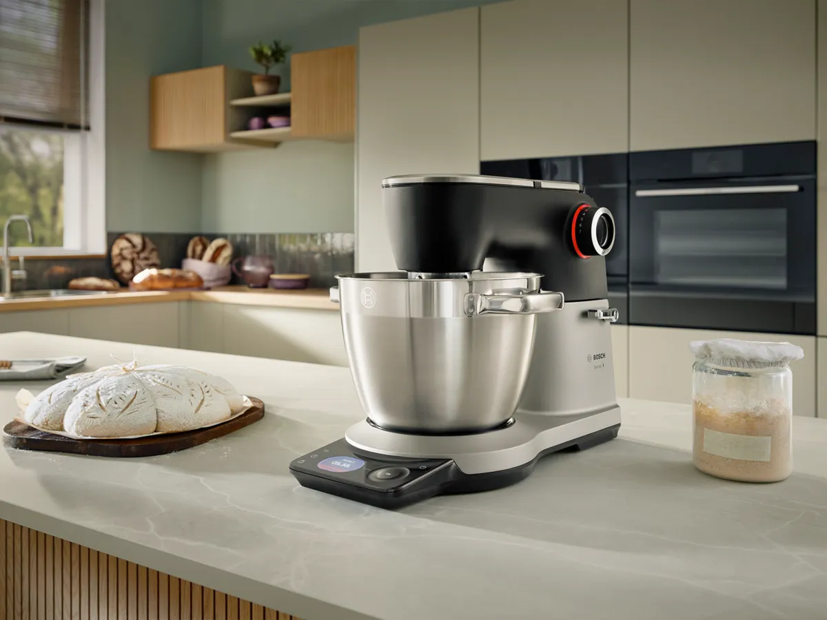 Bosch kitchen mixer on a counter with bread and jar, modern kitchen setting.