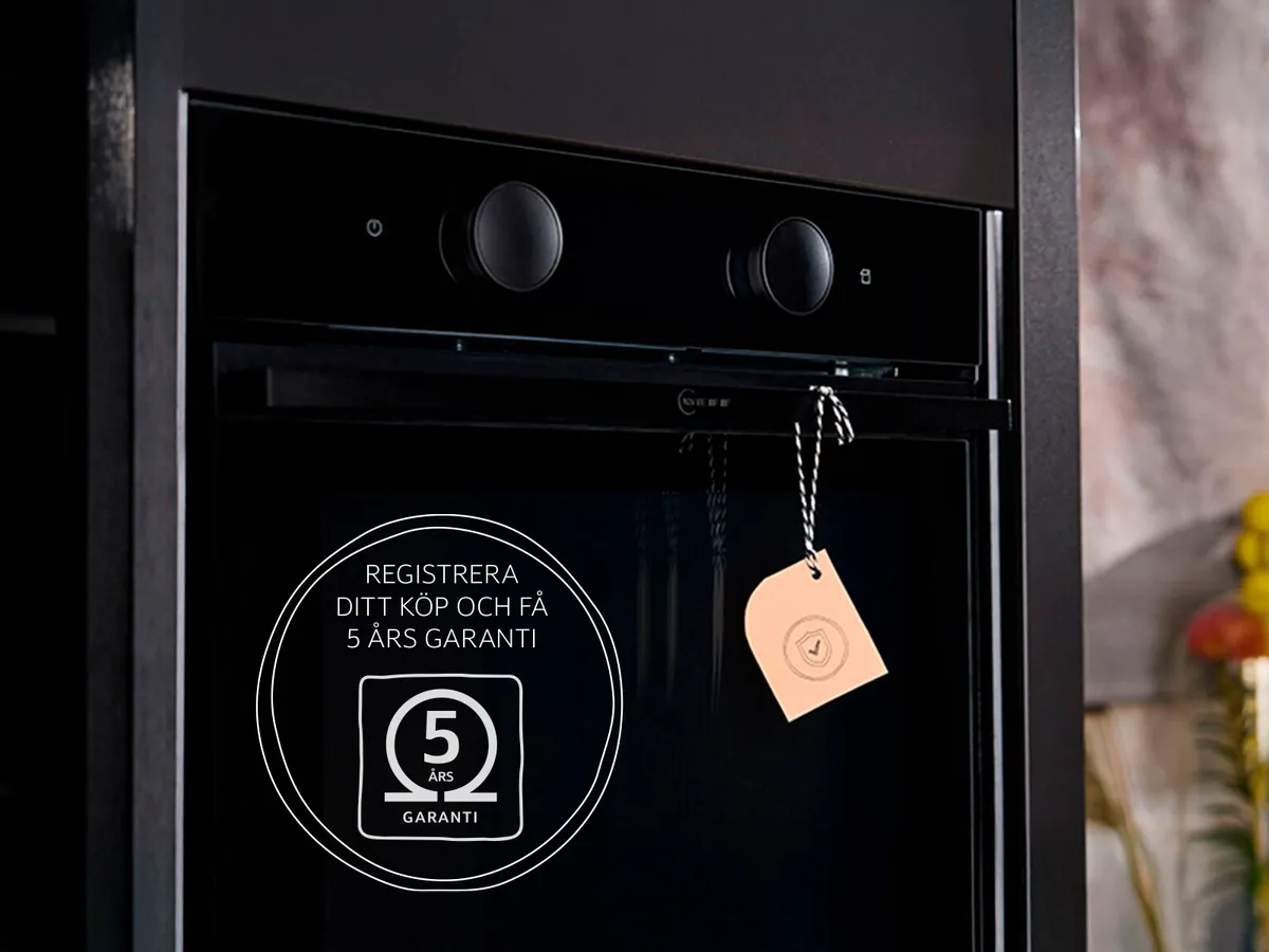 Neff svart inbyggd ugn med en hängande etikett på handtaget, samt ett 5-årigt garantimärke i bilden i ett modernt kök