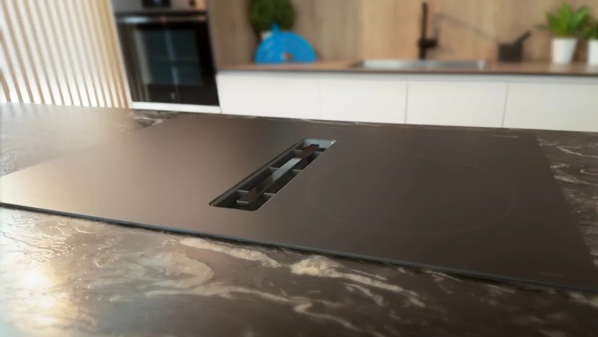 Encimera de cocina con placa de inducción con extractor integrado en acabado cristal negro mate en primer plano