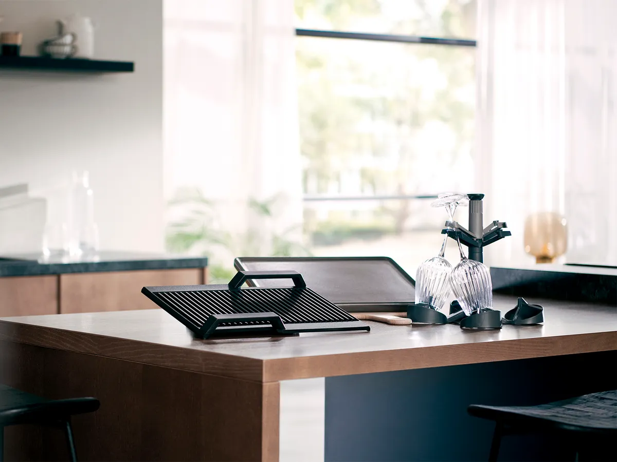 Modern kitchen with sleek black appliances, wooden countertop, and minimalist decor.