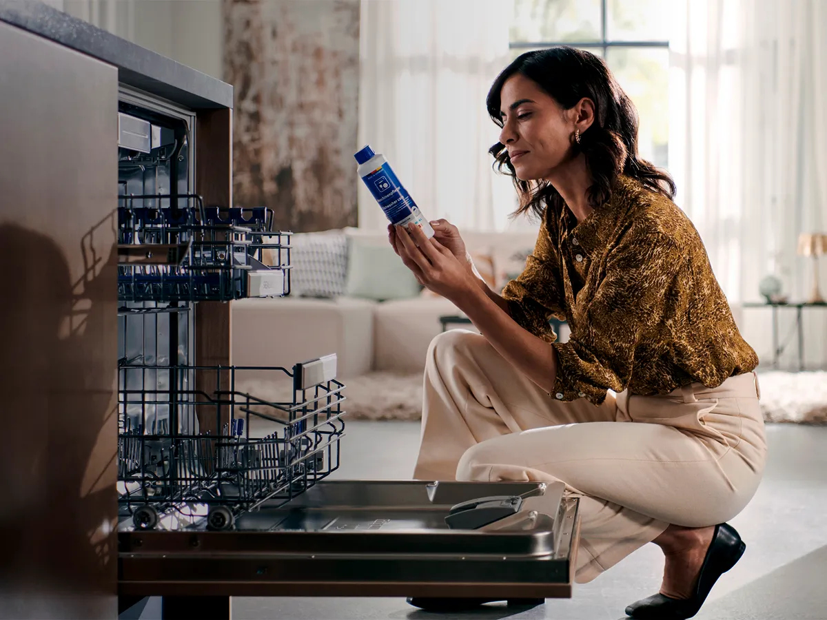 Woman in casual clothing sitting on floor, using smartphone, surrounded by home decor.