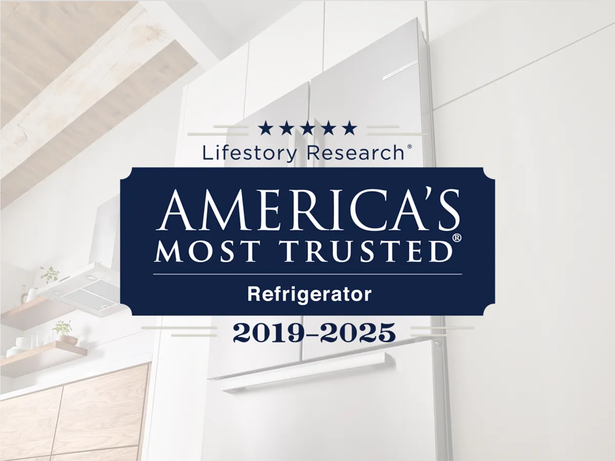 A sleek, modern stainless steel refrigerator with dual handles, set against a minimalist kitchen backdrop and a trust award label.