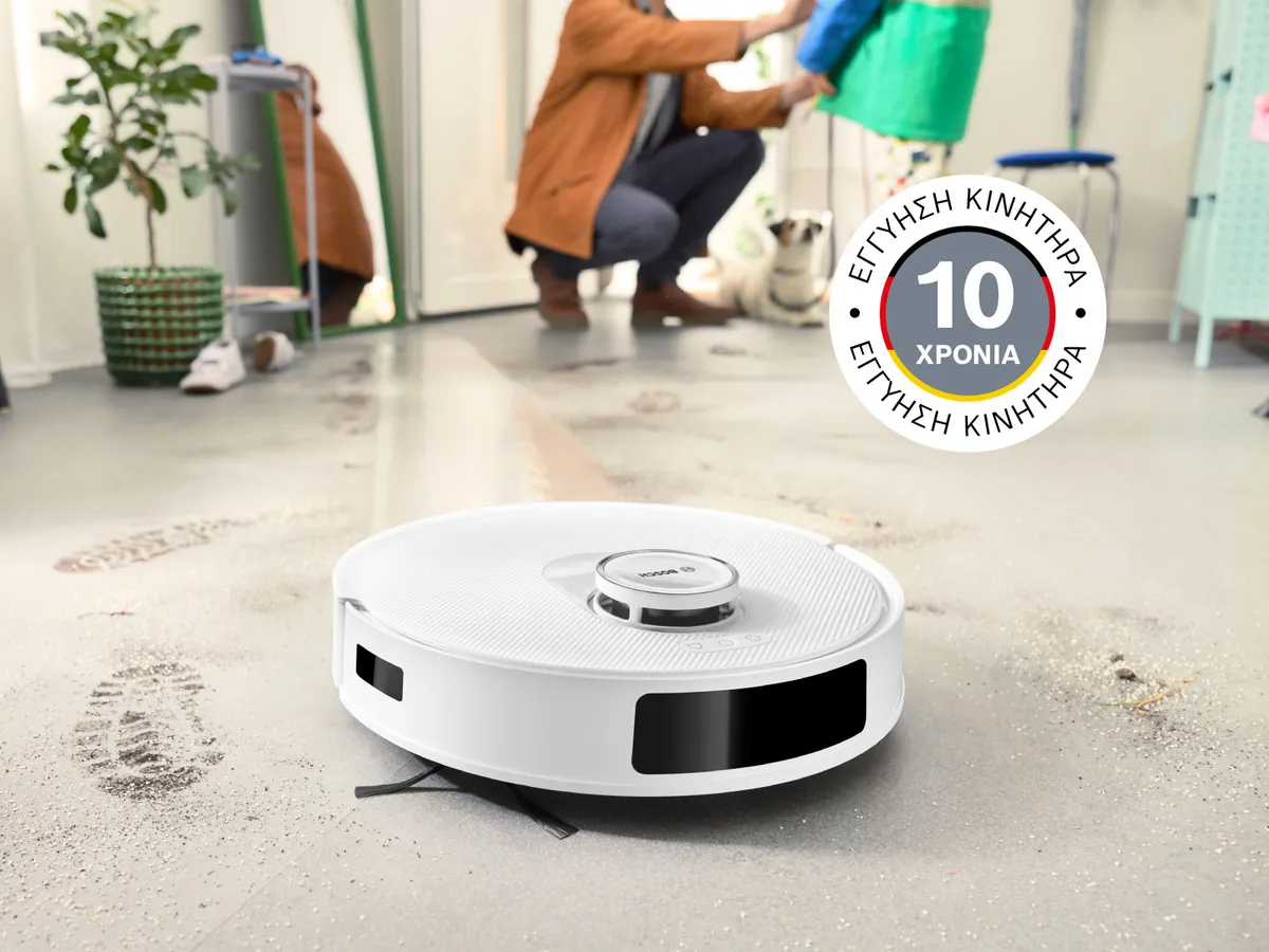 Η Spotless καθαρίζει τη λάσπη σε λευκά πλακάκια, με το σήμα 10ετους εγγύησης στον κινητήρα στην επάνω αριστερή γωνία.