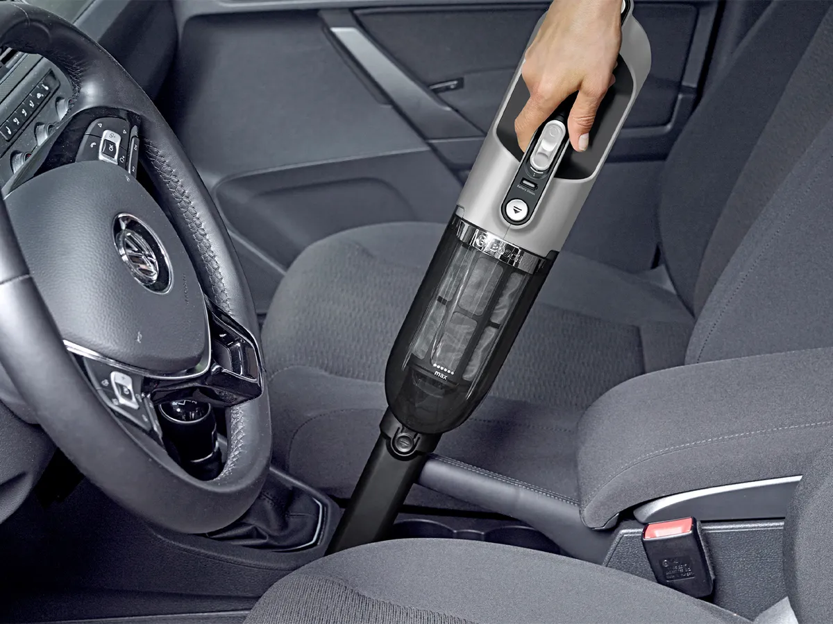 Person vacuuming car with handheld vacuum
