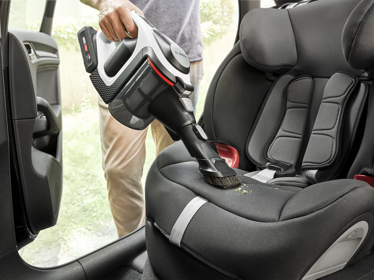 Person cleaning a car seat with an Unlimited vacuum