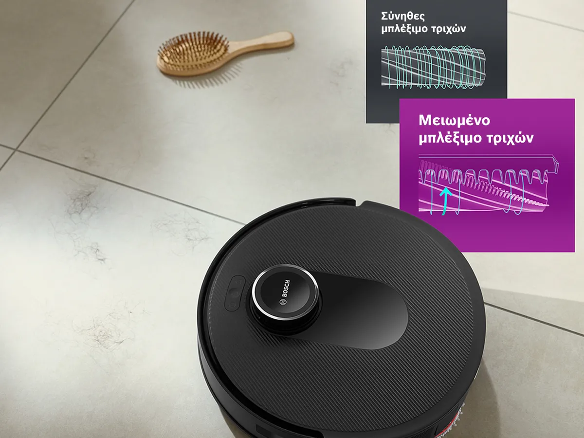 Η Spotless βρίσκεται πάνω σε ένα καθαρό δάπεδο με λευκά πλακάκια και με μια βούρτσα με τρίχες μαλλιών, αναδεικνύοντας τη λειτουργία μειωμένου μπλεξίματος τριχών.