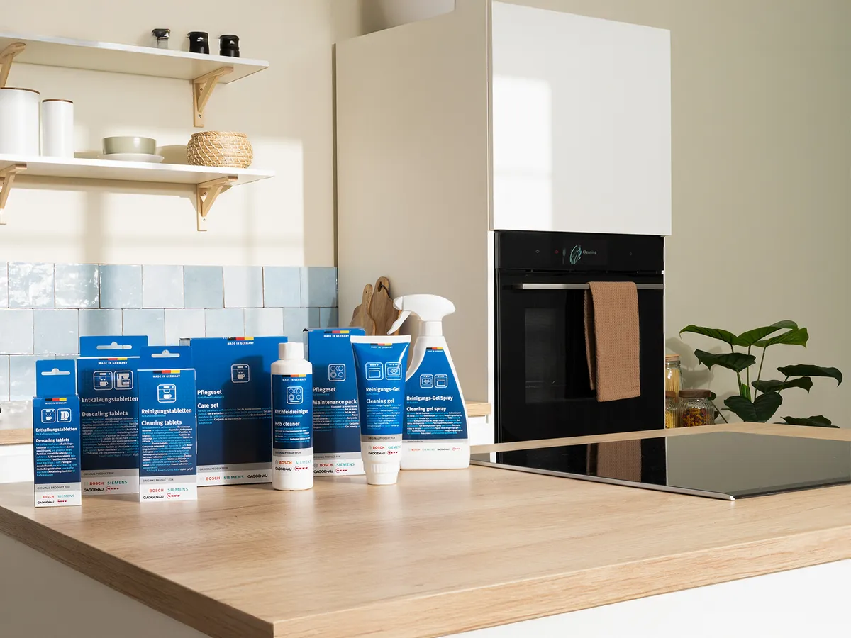 Un set di prodotti per la pulizia Bosch e Siemens, tra cui compresse decalcificanti, set per la cura e gel detergenti, sul tavolo della cucina.