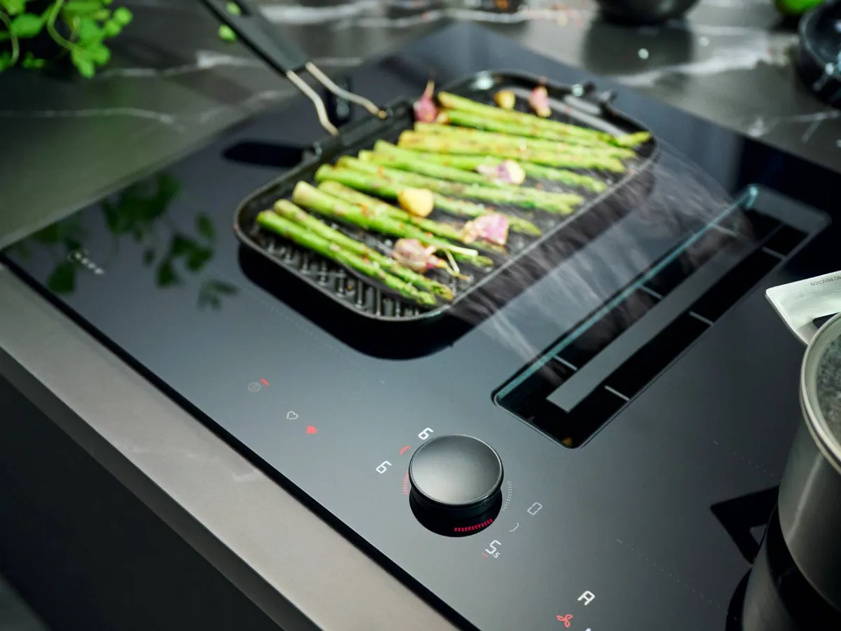 Pan cooking on extractor hood with vent on hob extracting steam