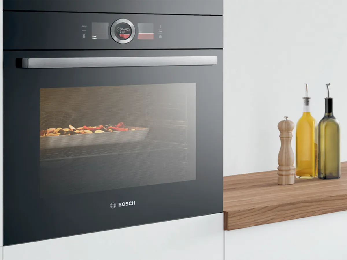 Фурна с храна, дървен плот, бутилки с олио, кухненски интериор.