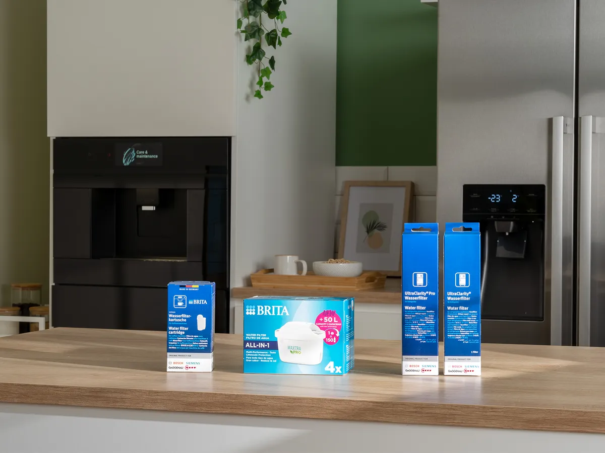 Un piano di lavoro in cucina con filtri e cartucce d’acqua Brita accanto a un distributore d’acqua, con elettrodomestici moderni sullo sfondo.