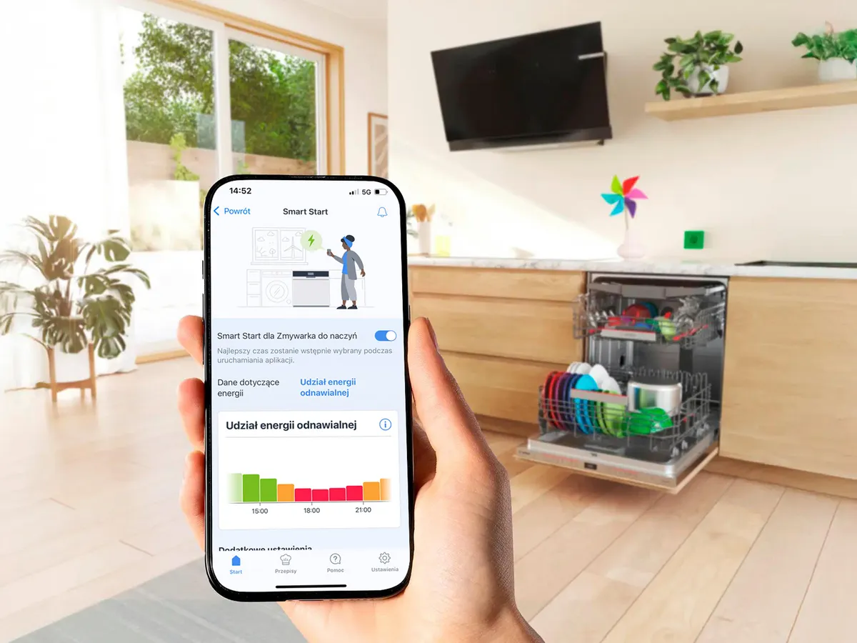 Dłoń trzyma smartfon, w tle otwarta zmywarka