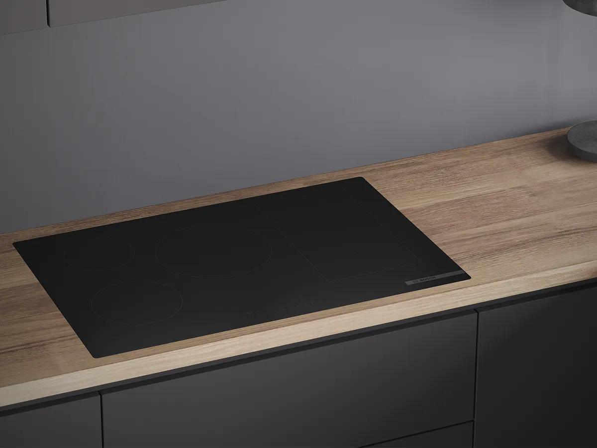 Moderno piano cottura a induzione Bosch nero opaco su un piano di lavoro in legno leggero.