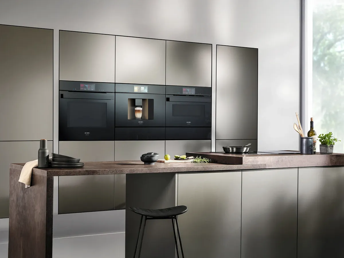 Modern kitchen with sleek gray cabinets, built-in appliances, and a wooden countertop.