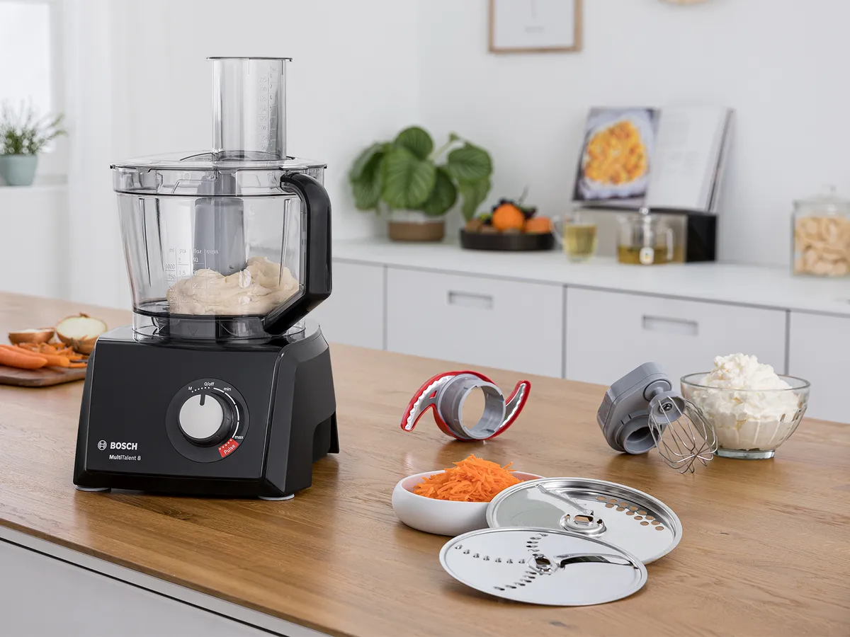 Here's an example:  Black Bosch food processor with dough, surrounded by attachments and prepared ingredients on a kitchen counter.