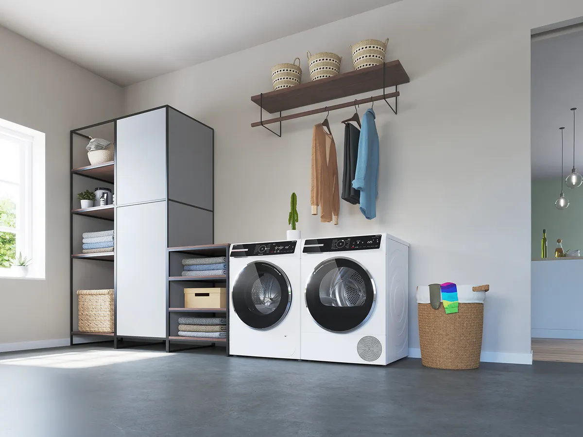 Buanderie moderne avec lave-linge et sèche-linge, piles de serviettes, meuble de rangement, vêtements suspendus et panier rempli d’articles colorés.