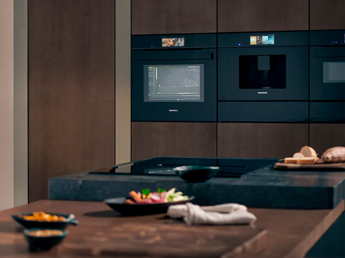 Moderne Küche mit Siemens Einbaugeräten, Freunde treffen sich zum stilvollen, gemütlichen Abendessen.