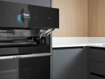 A person holds a smartphone displaying a smart appliance control app, set in a modern kitchen.