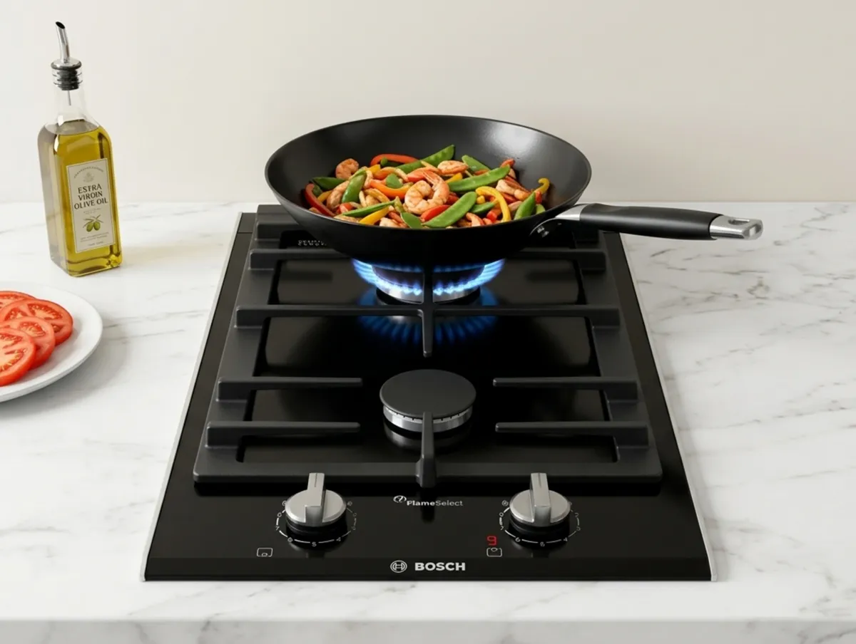A modern kitchen gas hob with colorful vegetables cooking in a wok.