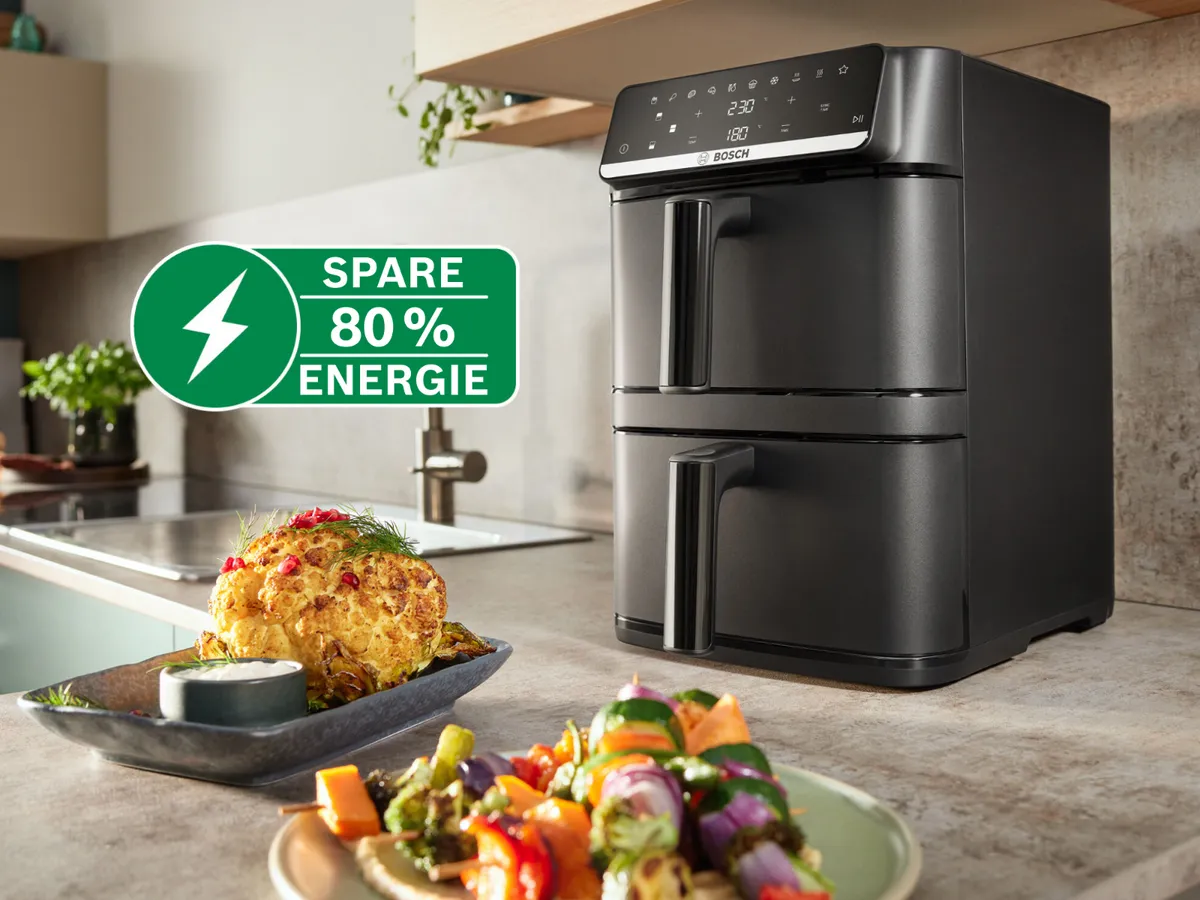 Bosch Doppel-Schubladen-Heißluftfritteuse auf Küchenarbeitsplatte mit geröstetem Essen, betont "SPARE 80% ENERGIE" und kein Vorheizen.