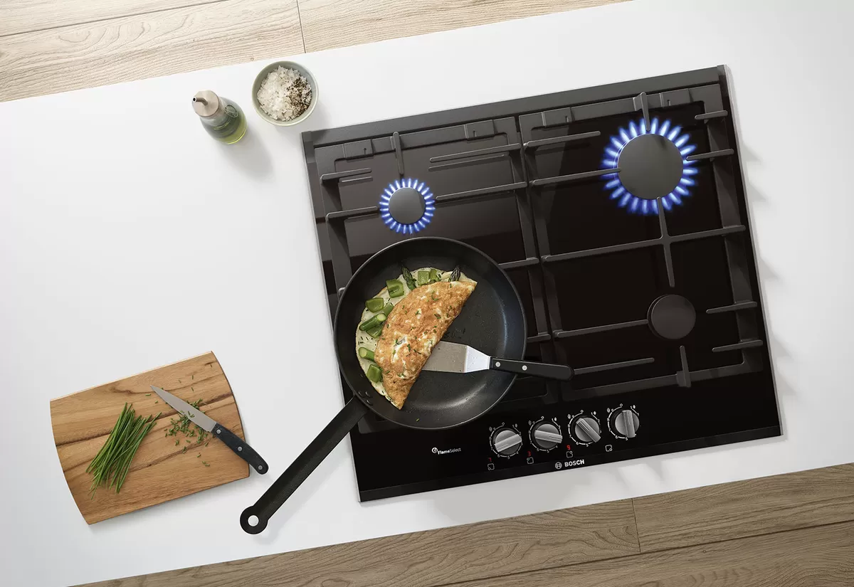 Gaz ocağı yemek pan, doğranmış sebze ve ahşap yüzeyde yemek aletleri.