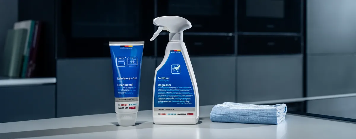 Temizlik ürünleri, sprey şişe ve minimalist, koyu tonlu bir ortamda bir masada havlu.