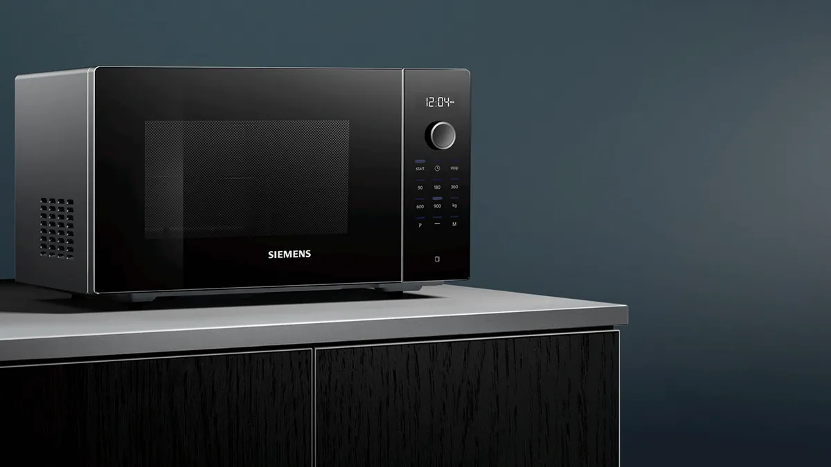 Sleek kara Siemens mikrodalga fırını koyu ahşap bir dolapta, zaman ve sıcaklık gösterir.