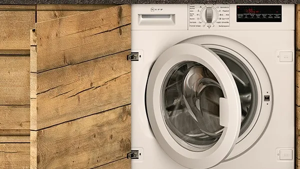 A washing machine located in a kitchen with wooden walls, showcasing a blend of functionality and rustic design.